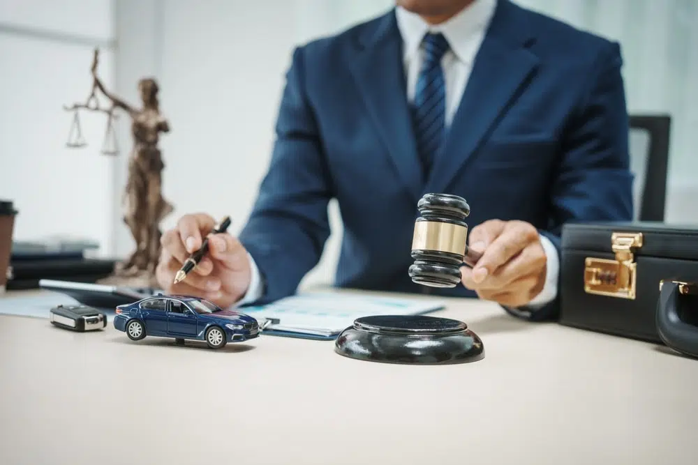 Car Accident Lawyer Car accident lawyer sitting by their desk with a gavel in hand and toy car beside it