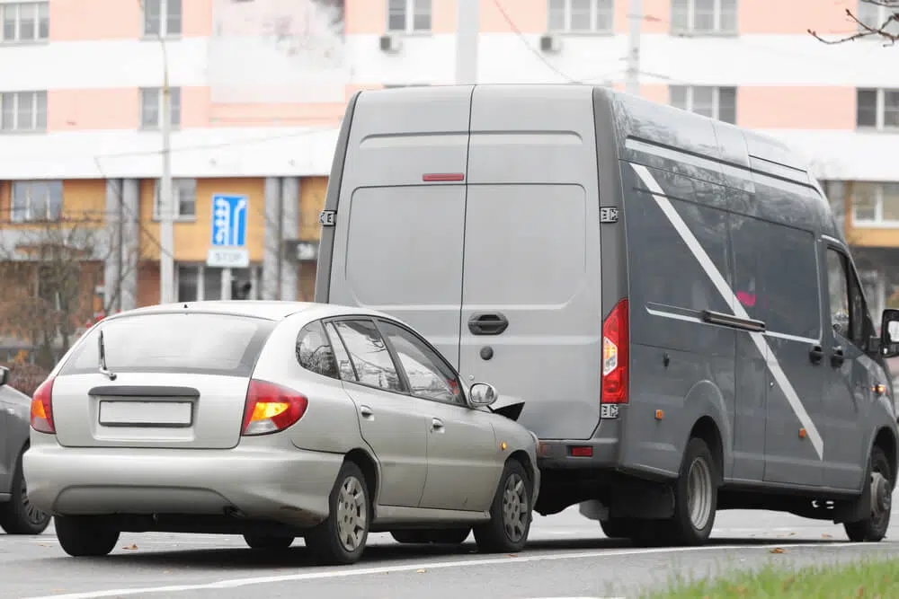 A photo of a car crashing into the back of a truck